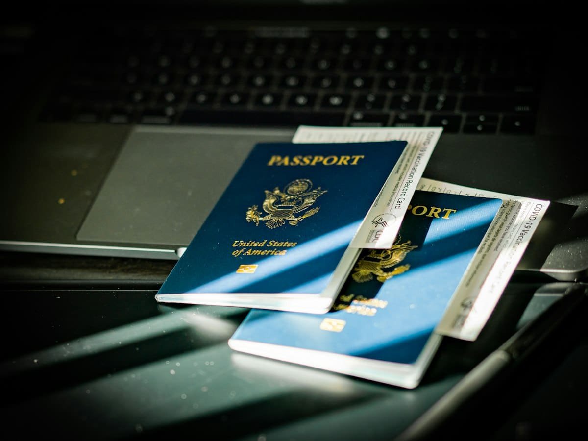 Two closed US passports and vaccination cards resting on a laptop